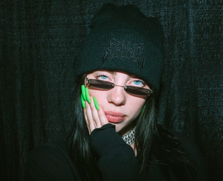 Billie wearing all black outfit with black heavy metal beanie with green acrylic nails and shades 